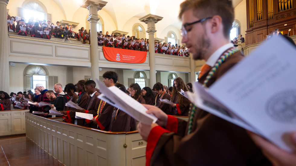 Students hold ceremony programs and sing hymn