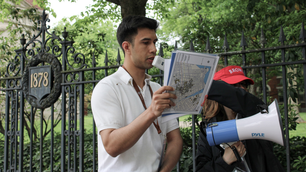 young man reading from notes on tour of campus