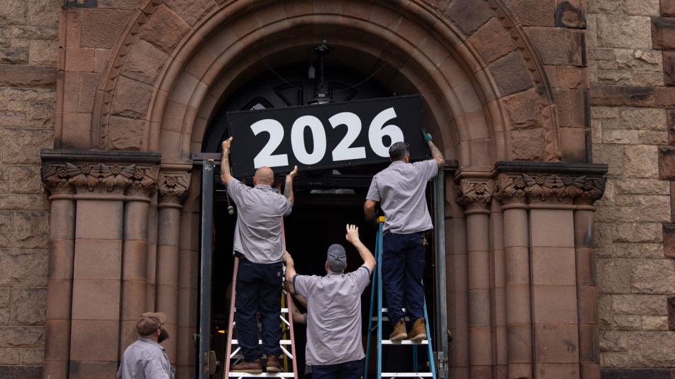 Facilities workers install a 2026 sign 