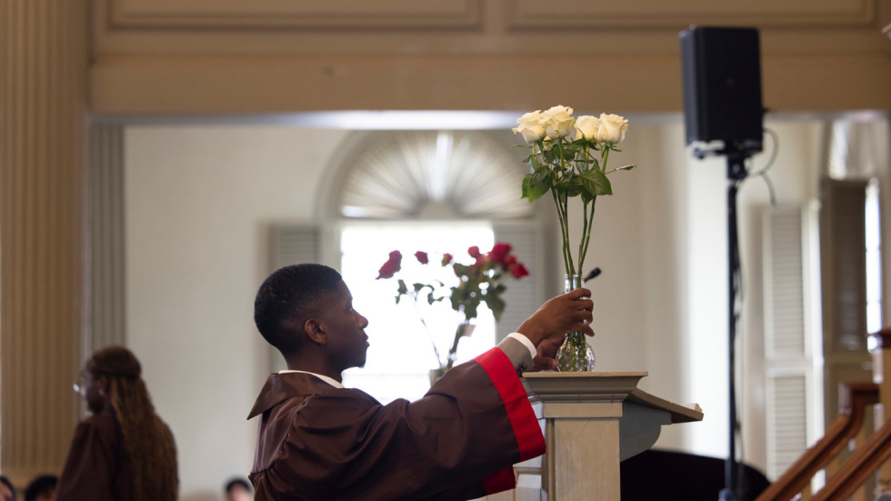 Students place vase of roses on altar