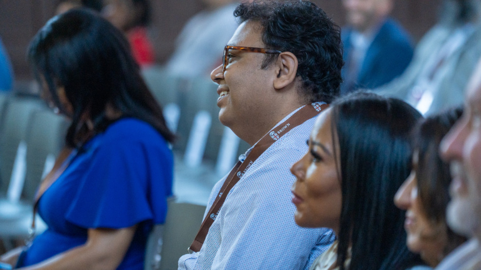 A Brown staff member sits among others, rows of attendees at the small business supplier summit. 