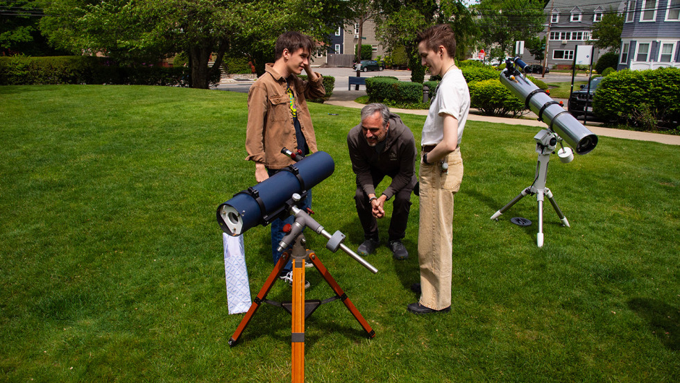 three people looking at a telescope