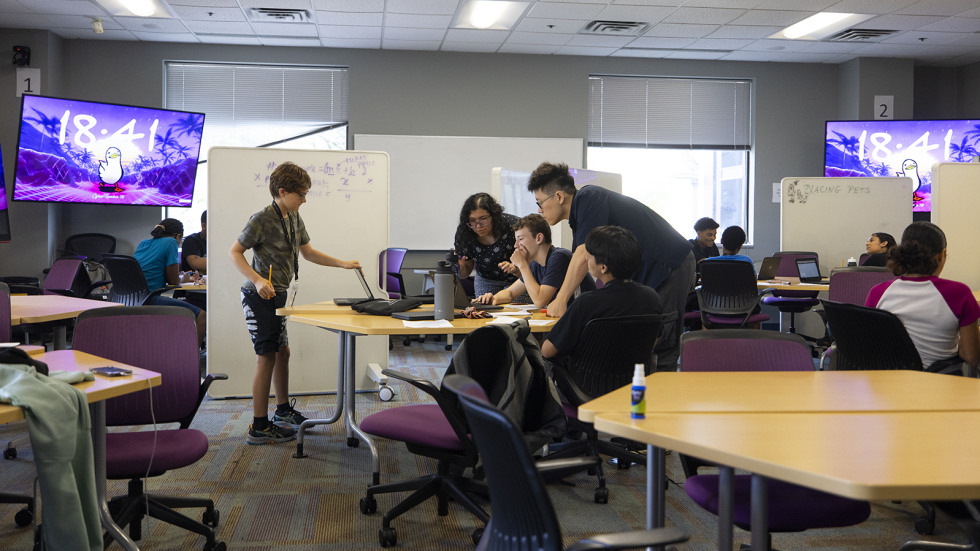 students in the Brown Collegiate Scholars program work together around a table to solve math equations as part of a algebra class.