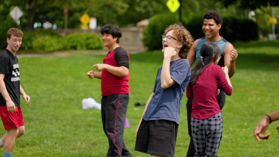 providence teens smile and laugh together playing a game on a green space on Browns' campus. 