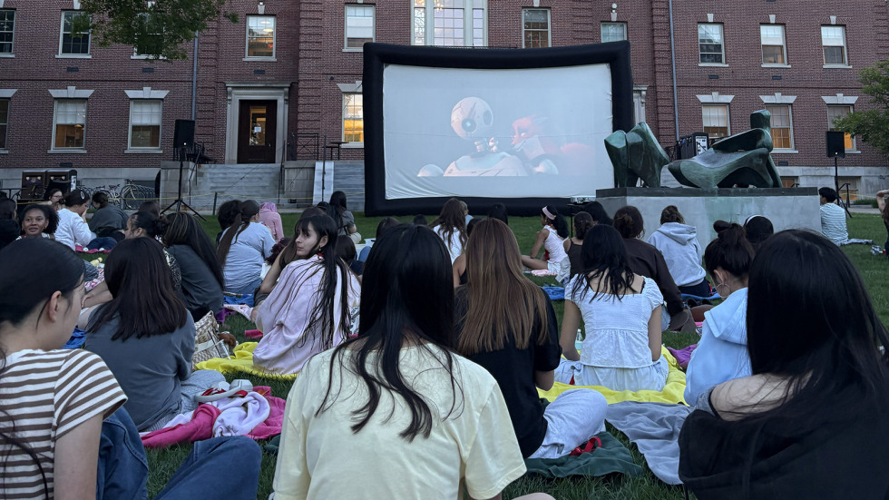 Students watch a movie outdoors on the College Green