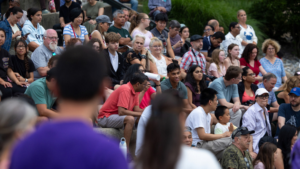 a crowd or providence community members look toward the river at the waterplace park for a full waterfire providence lighting