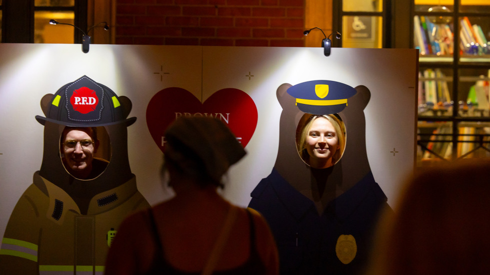 families at waterfire providence put their faces in cut out holes of Bruno the bear, brown's mascot