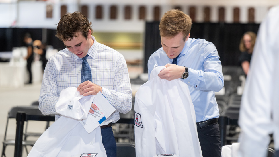 two male students picking up their white coats