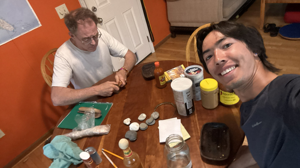 Two people at a table doing wood carving