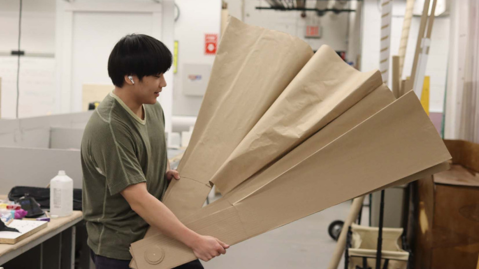Person holding a giant cardboard folding fan
