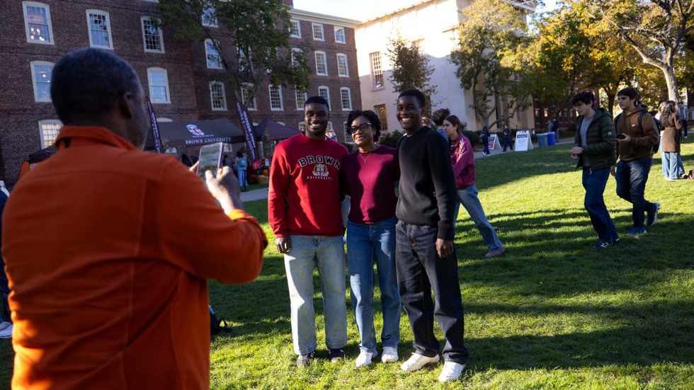 a family stops on the College Green to take a family photo together.