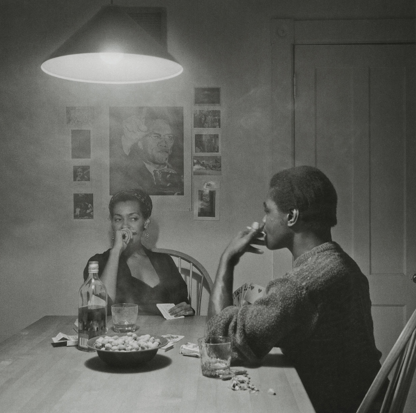 Photo of two people playing cards, smoking and drinking by Carrie Mae Weems (b&w)