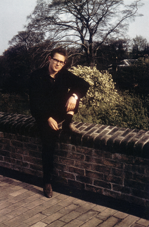 Kosterlitz in 1965, sitting on a brick wall