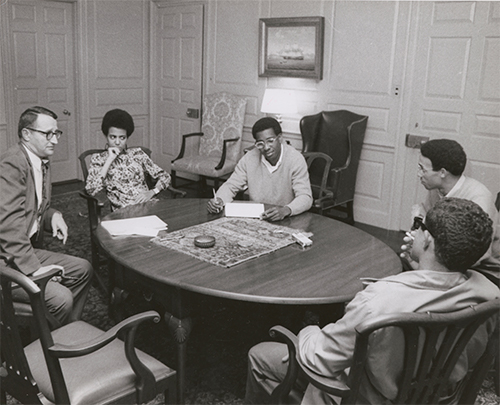 Black students sitting around a table with a Brown administrator
