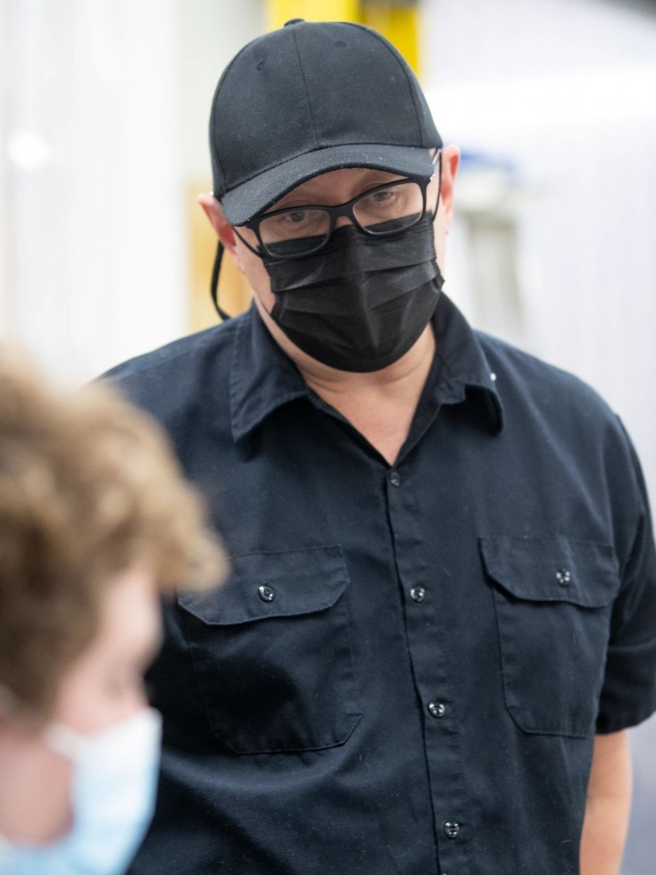 Paul Myoda wearing a face mask and looking over a student's shoulder 