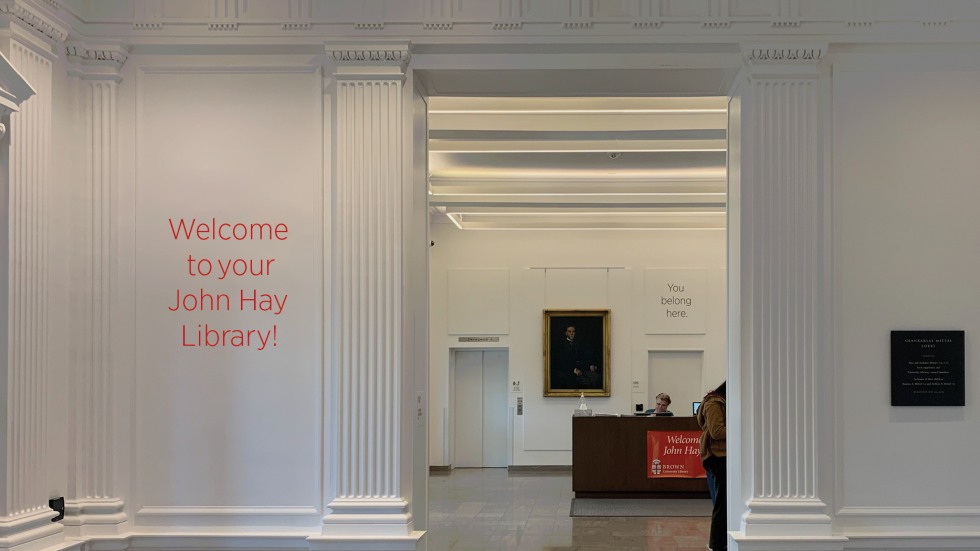 White columned foyer with a wall decal that reads "Welcome to your John Hay Library!"
