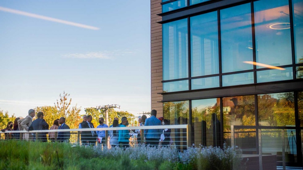 people gathered on a second-story wooden deck with plants 