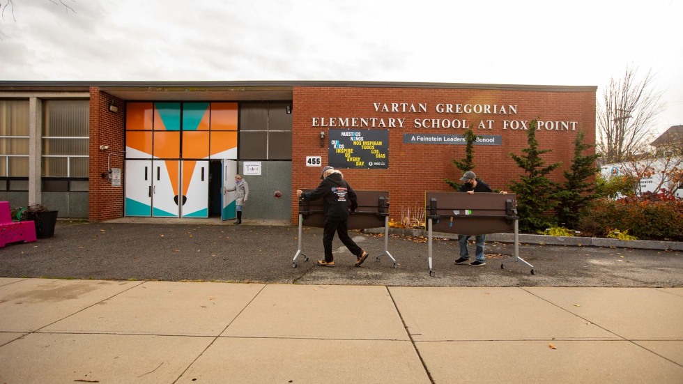 two people moving rolling tables into Vartan Gregorian Elementary School