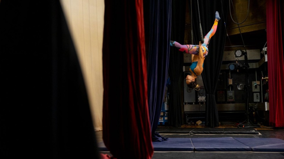 Woman hanging upside down from a trapeze on a stage