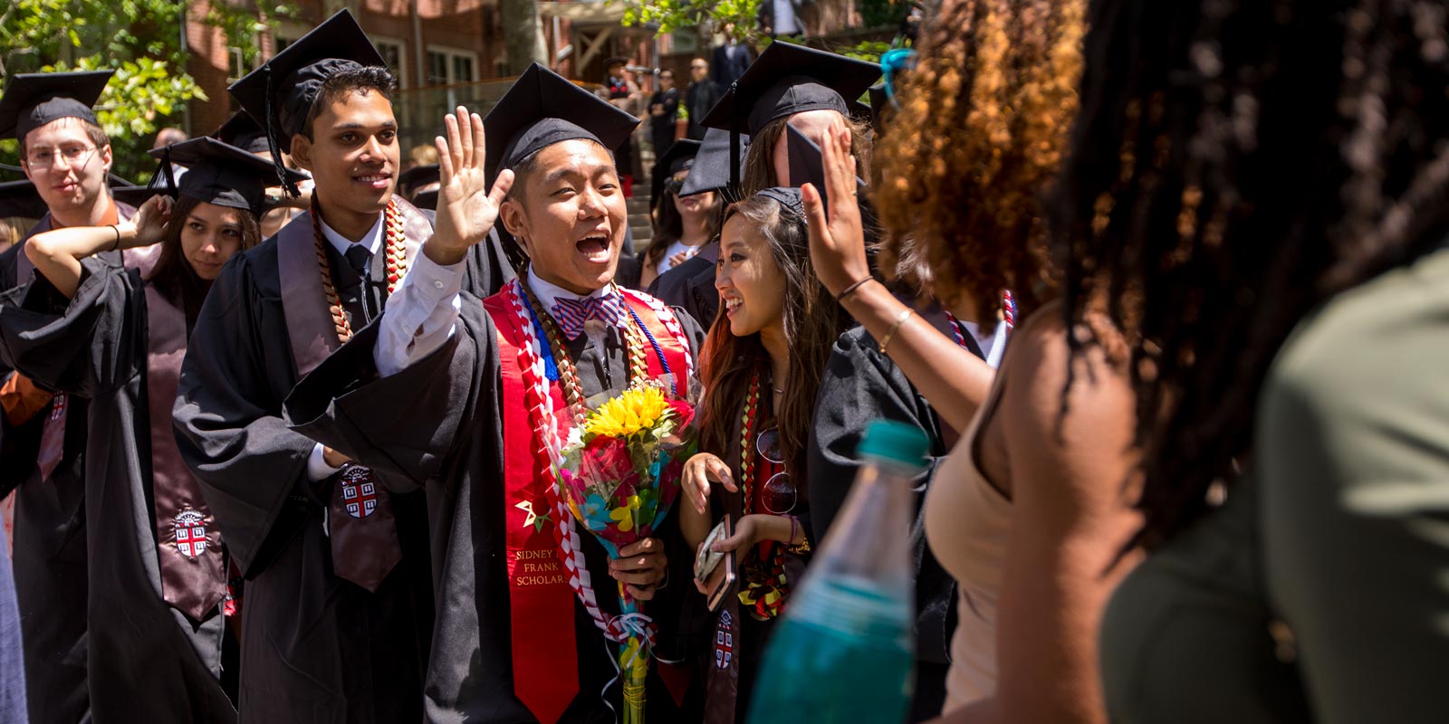 Will Truong high-fived an alumna during the procession, a treasured Brown tradition where students and alumni celebrate one another.